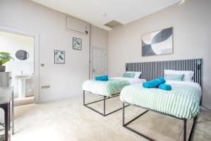 two beds in a room with white walls and blue pillows at 5 Bedroom House in Ashton-under-lyne with Free Parking and Easy Access to City Centre in Stalybridge
