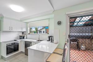 a kitchen with white cabinets and a sink at Tranquility Place in Evans Head