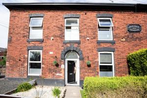 a brick building with a door and a sign on it at 5 Bedroom House in Ashton-under-lyne with Free Parking and Easy Access to City Centre in Stalybridge