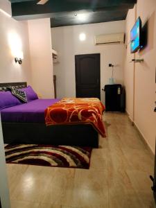 a bedroom with a purple bed and a flat screen tv at guest house carolina in Colva +2 photos