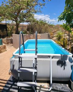 a pool with two chairs and a table and a swimming pool at Unpretentious peaceful Cottage in Clanwilliam