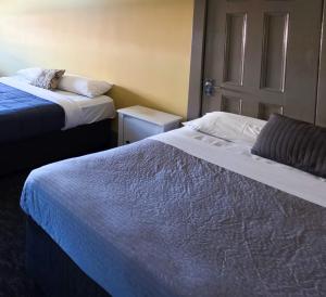 a room with two beds and a door at Cessnock Hotel Hunter Valley in Cessnock