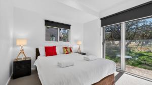 a white bedroom with a large bed and a window at Humffray 3 in Dinner Plain