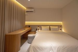 a bedroom with a bed with a desk and a bed sidx sidx sidx at H Avenue Hotel Gwangju Cheomdan in Gwangju