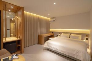 a bedroom with a white bed and a bathroom at H Avenue Hotel Gwangju Cheomdan in Gwangju