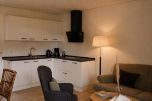 a kitchen with white cabinets and a living room at KragenæsHus in Torrig