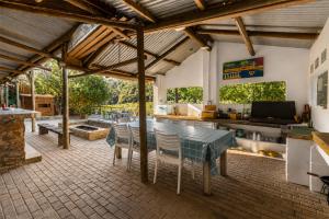 a patio with a table and chairs and a couch at Kaaimans River Deckhouse in Wilderness