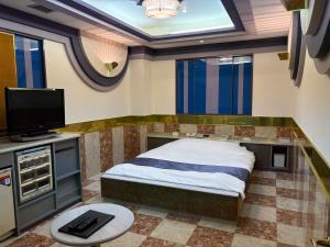 a small bedroom with a bed and a tv at HotelG7 in Tokyo