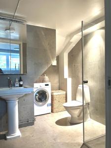 a bathroom with a toilet and a washing machine at Badklippan in Stockholm