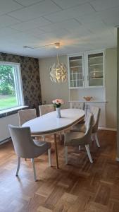 a dining room with a white table and chairs at Villa Skäris in Falkenberg