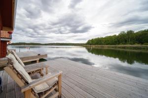 a wooden dock with two chairs on a lake at Kung Solsta in Blankaholm