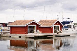 a small red house on a dock with a boat at Kung Solsta in Blankaholm