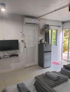 a kitchen with a refrigerator and a television in it at บ้านเล็กในป่าใหญ่ พัทลุง in Ban Nai Mon