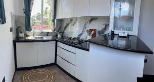 a kitchen with white cabinets and black counter tops at Kandana bliss villa in Kandana
