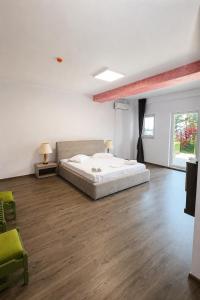 a large white bedroom with a bed and wooden floors at BC Aprilia in Corbu +45 photos