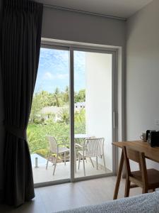 a room with a sliding glass door with a table and chairs at Hidden Bay Chaloklam in Chaloklum
