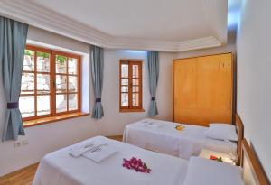 two beds in a room with two windows at Çınarlar Apart KC Blok in Kaş +11 photos
