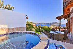 a swimming pool with chairs and a table on a patio at Çınarlar Apart KC Blok in Kaş