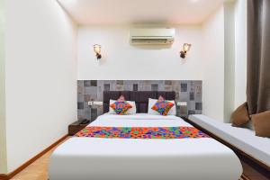 a bedroom with a large white bed with colorful pillows at FabHotel Harsh Paradise - Malviya Nagar in Jaipur