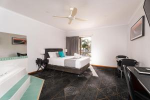 a bedroom with a bed and a tub and a table at Hotel Renmark in Renmark +43 photos
