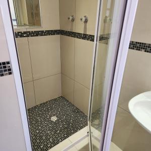 a shower with a glass door next to a sink at Shirleys Place in Brackenfell +10 photos