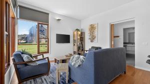 a living room with two blue chairs and a window at Triggerplant 2 in Dinner Plain +7 photos