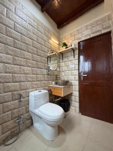 a bathroom with a white toilet and a brick wall at Tora House in Nagar