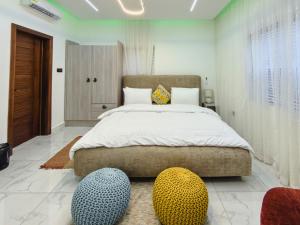 a bedroom with a large bed with two ottomans at Horizon Apartment at THE HIDDEN DOMUS I Pool View in Accra