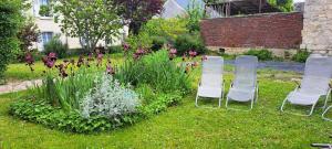a group of chairs in a garden with flowers at Gite ETAPE A COUCY in Coucy-le-Château-Auffrique