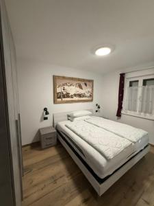 ein Schlafzimmer mit einem Bett und einem Gemälde an der Wand in der Unterkunft Chalet La Viola in Alba di Canazei