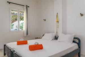 a bedroom with a white bed with two orange pillows at Perasma Studios 12 in Kipri