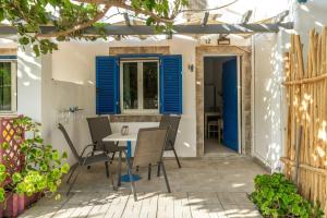 a patio with blue shutters and a table and chairs at Perasma Studios 12 in Kipri