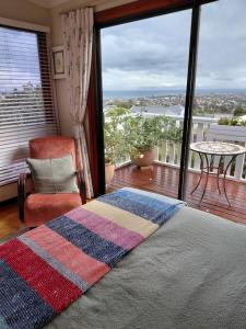 a bedroom with a bed and a balcony with a view at Martha's Place in Gordonʼs Bay