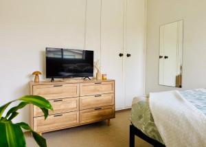 a bedroom with a television on a wooden dresser at Cozy Bondi ROOM - Beach life and Local Host! Free Parking in Sydney