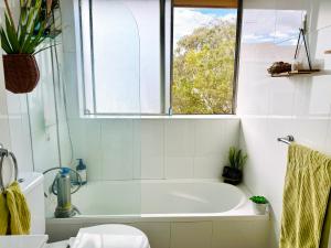 a white bathroom with a tub and a window at Cozy Bondi ROOM - Beach life and Local Host! Free Parking in Sydney +8 photos
