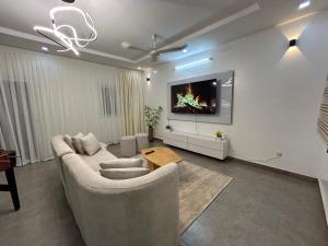 a living room with a couch and a tv on a wall at Villa Djenné électricité 24h in Bamako