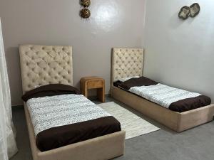 two beds sitting next to each other in a room at Villa Djenné électricité 24h in Bamako