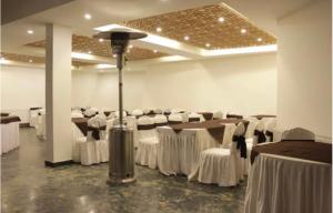 a banquet hall with white tables and white chairs at Hotel Meridien Riverfront in Srinagar