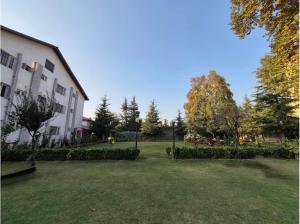 a park with a building and a grass yard at Hotel Meridien Riverfront in Srinagar