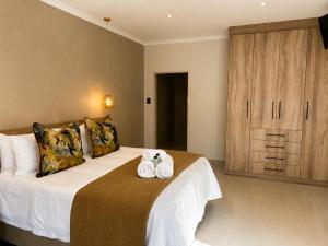 a bedroom with a large bed with towels on it at Hanan Guesthouse in Thabazimbi