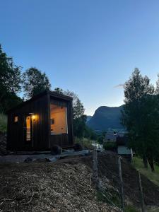 a small cabin in a field with mountains in the background at Minihouse Stryn in Oppstryn