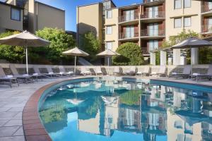 a pool at a hotel with chairs and umbrellas at Rendezvous Heritage Hotel Queenstown in Queenstown