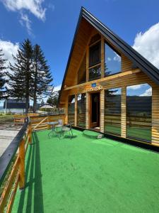 a wooden house with a green lawn in front of it at Vlasic Odmor - Villa Krajina V in Vlasic