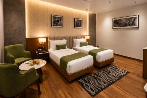 a hotel room with two beds and a table and chairs at Four Leaf Hotel Dehradun in Dehradun +36 photos