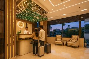 a couple standing at a counter in a hotel with luggage at Four Leaf Hotel Dehradun in Dehradun