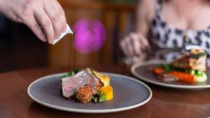 a person is putting a piece of meat on a plate at The Royal & Fortescue Hotel in Barnstaple