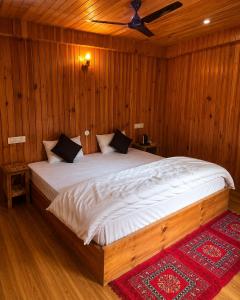 a bedroom with a large bed with wooden walls at KOKILARIVERSONGHomesaty in Banjār