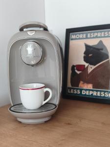 a coffee machine with a cup on a plate next to a picture at Słoneczne studio in Głuszyca