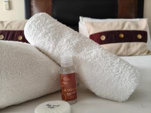a towel and a bottle of hand sanitizer on a bed at The Rest Place B&B in East London