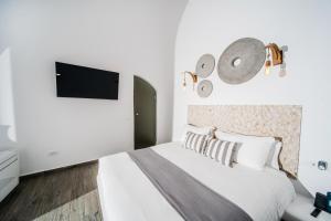 a bedroom with a bed and a tv on the wall at Angel Luxury Suites in Fira +60 photos